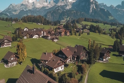 Drohnenaufnahme eines bayerischen Dorfs vor Alpenkulisse – Symbolbild für geerbte Immobilien im Ostallgäu