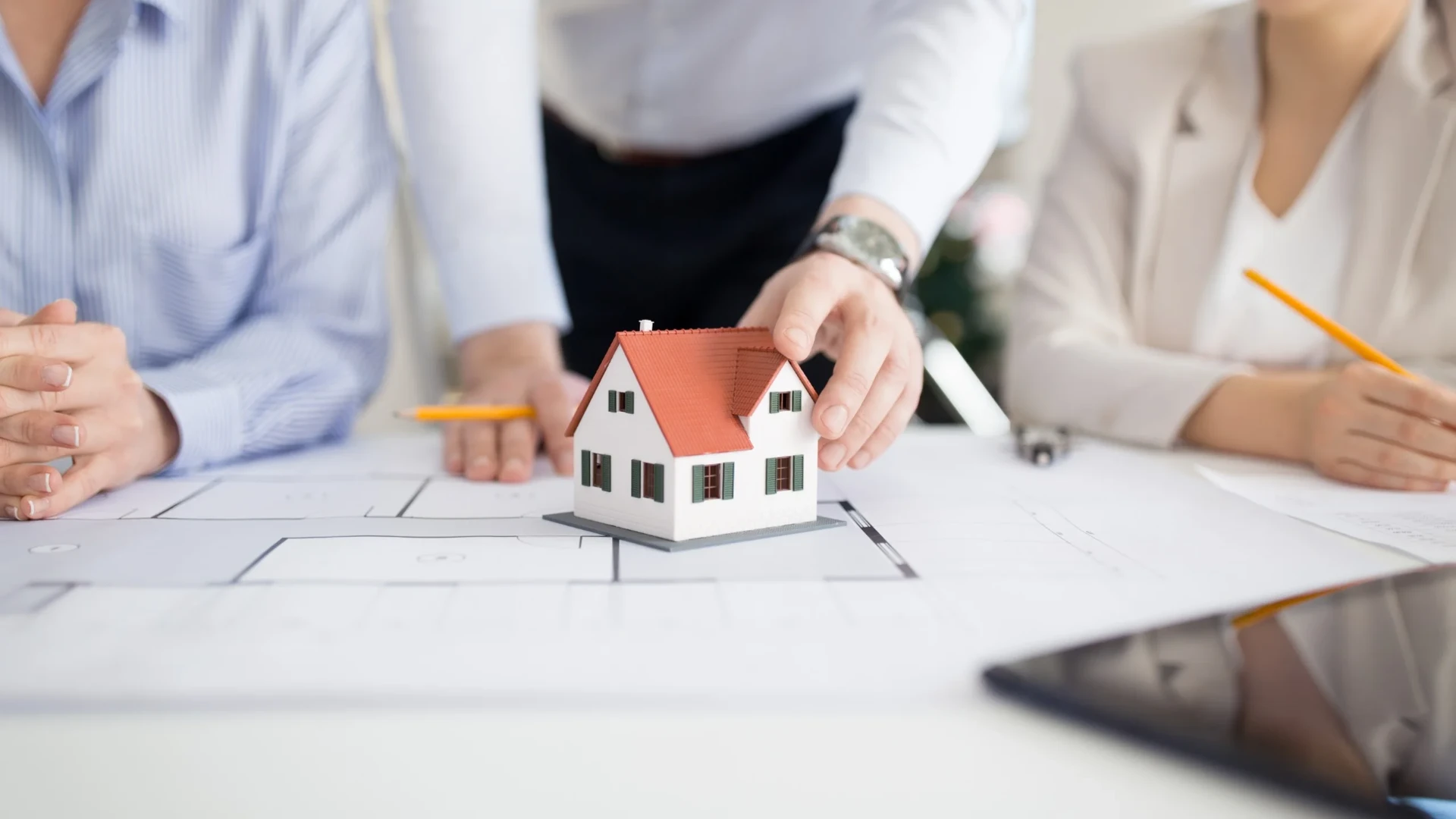 Modellhaus auf Bauplänen vor Laptop – Immobilienverkauf, Vermietung und WEG-Verwaltung im Allgäu mit RGI Immobilien